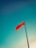 A single red flag is prominently displayed against a clear blue sky, attached to a tall pole.