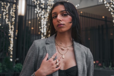 Close-up of a model showcasing layered streetwear accessories under city lights at dusk.