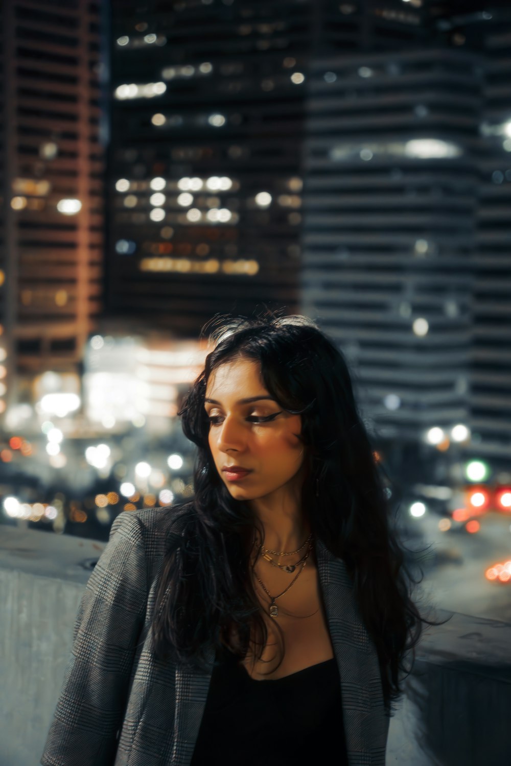 a woman standing in front of a cityscape at night