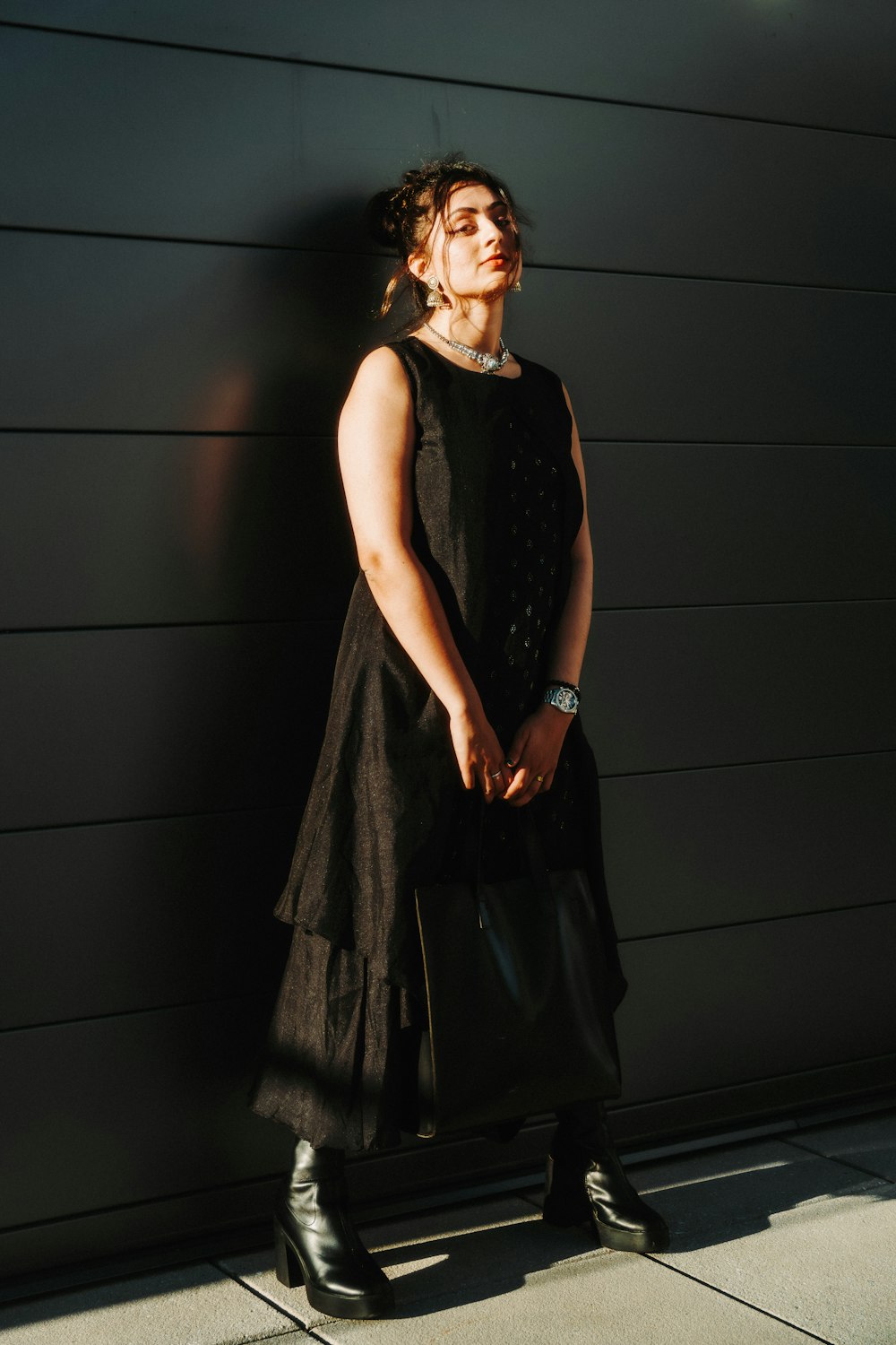 a woman in a black dress standing against a wall