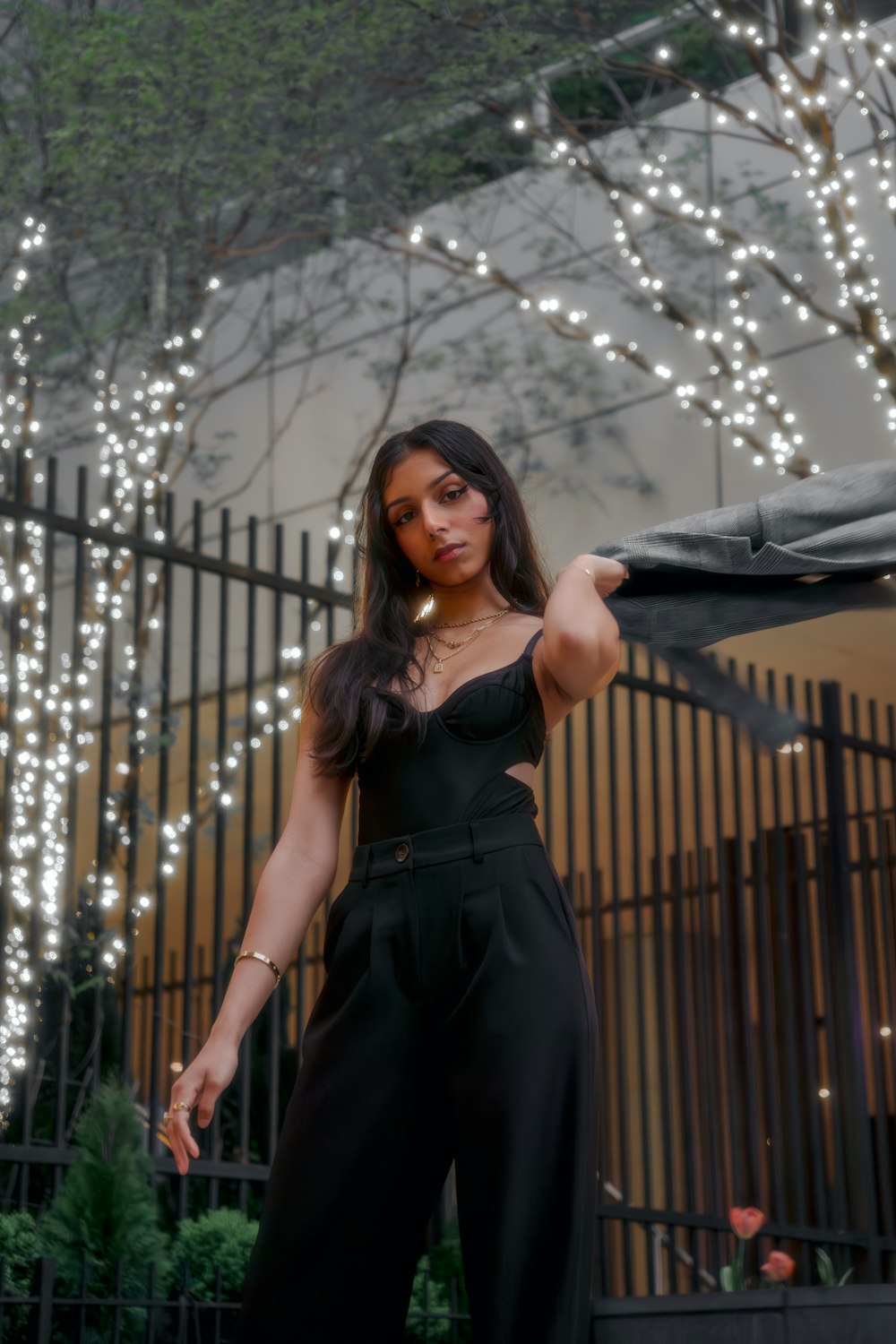 a woman in a black jumpsuit holding a black umbrella