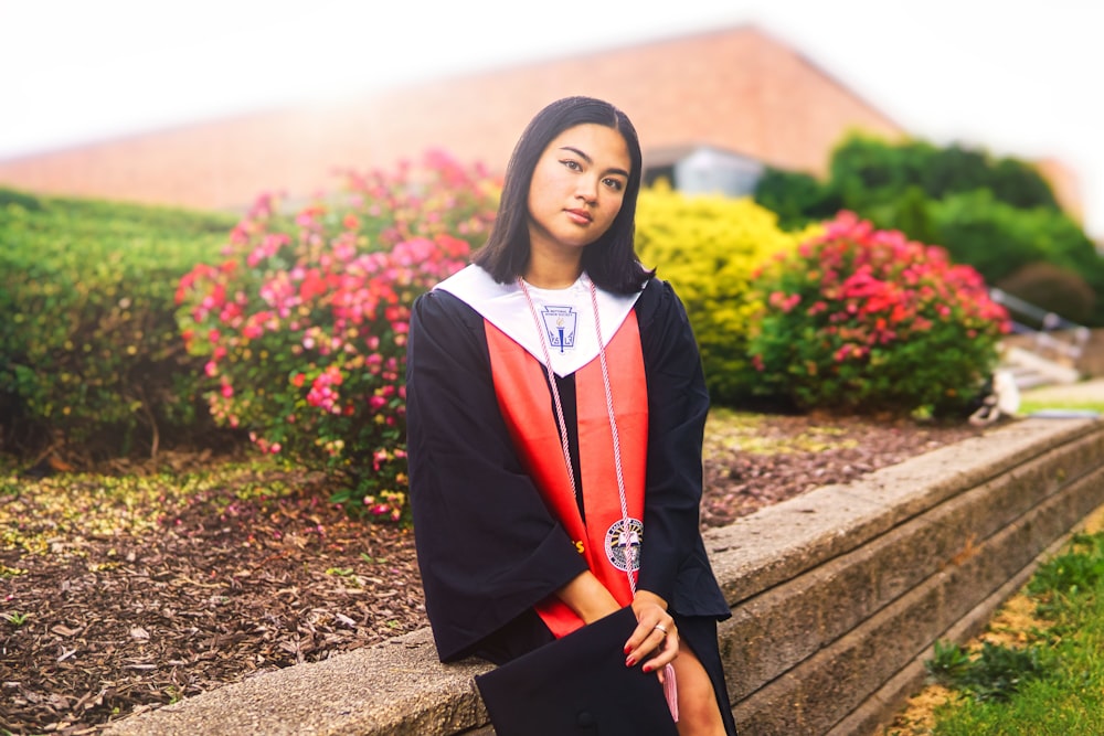 a woman in a graduation gown leaning on a wall