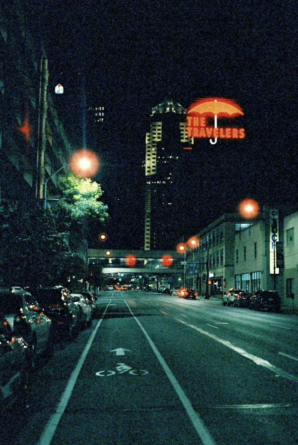 a city street at night with cars parked on the side of the road