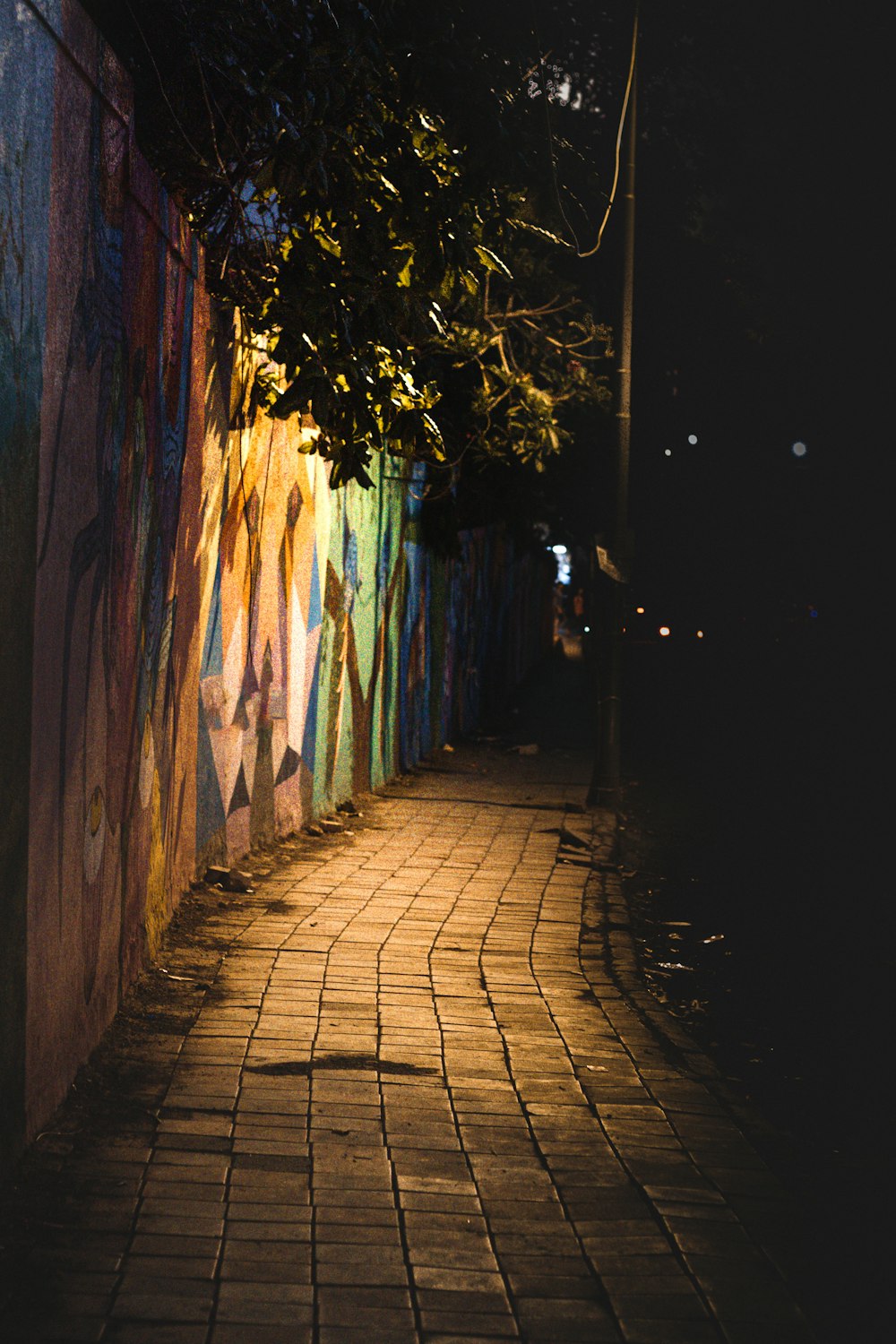 a brick sidewalk next to a wall covered in graffiti