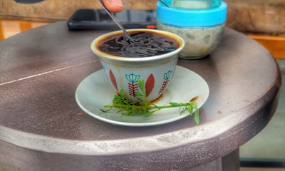 Olive green ceramic cup filled with herbal tea beside an open journal.