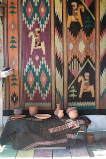 A vibrant western outfit laid out on a wooden table with hand-thrown pottery beside it.
