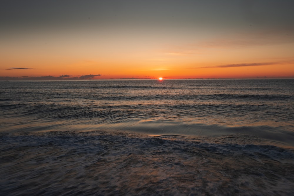 the sun is setting over the ocean with waves