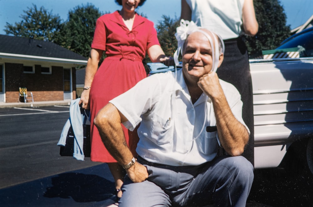 a man sitting on the back of a car next to a woman