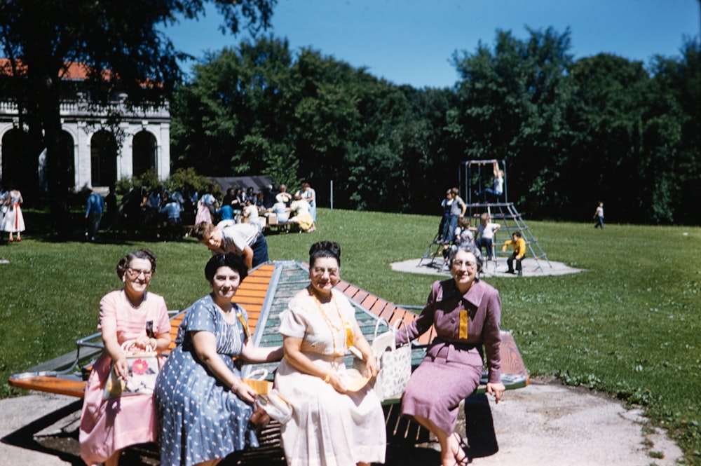 a group of women sitting on top of a wooden bench