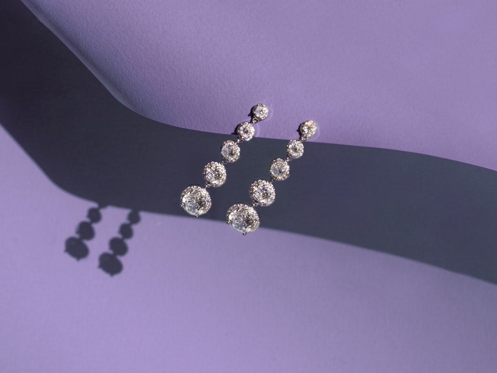 a pair of diamond earrings on a purple background