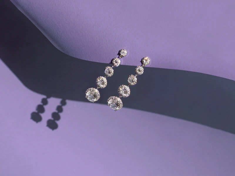 A pair of diamond earrings on a purple background