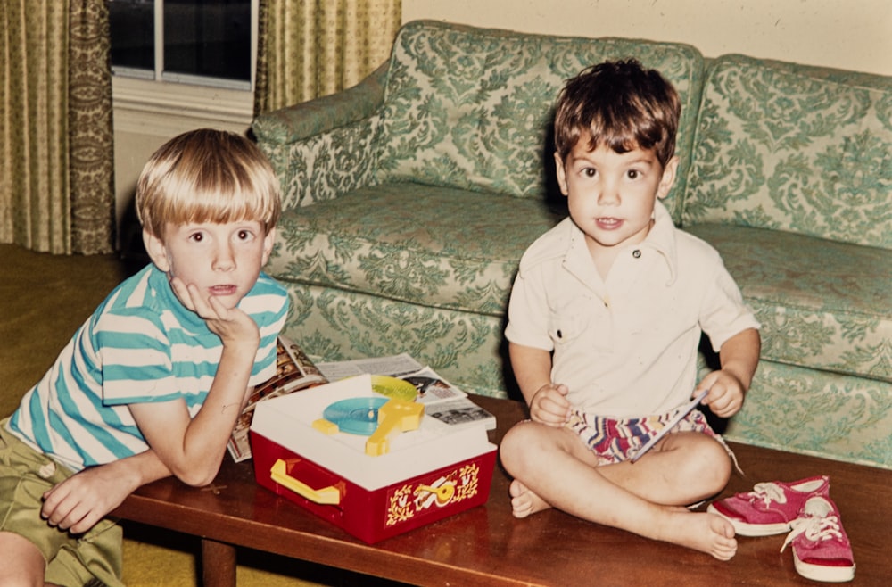 two young boys sitting on a coffee table