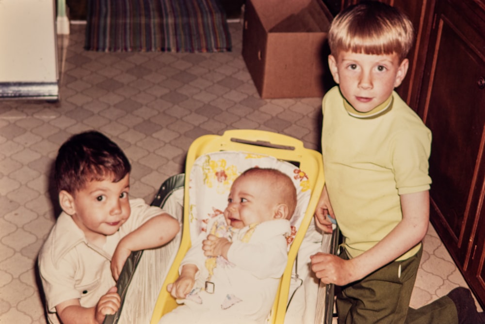 two young boys standing next to a baby in a stroller