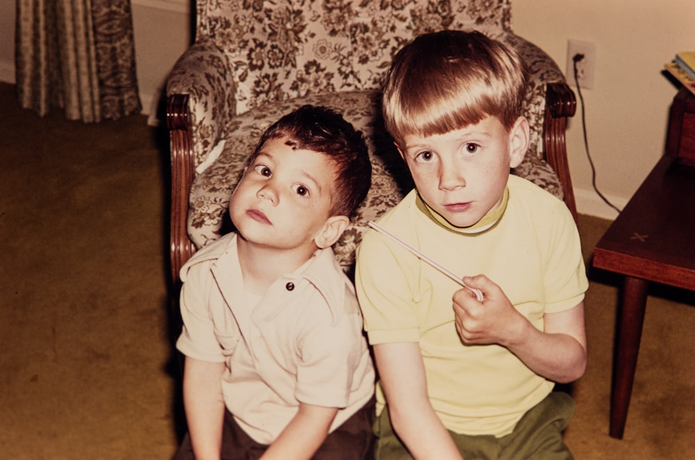 two young boys sitting on a chair in a living room