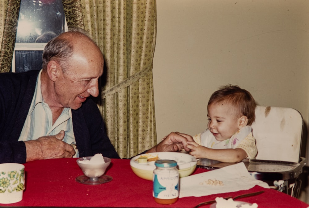 an older man and a young child sitting at a table