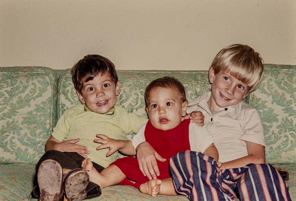 three children sitting on a couch smiling for the camera