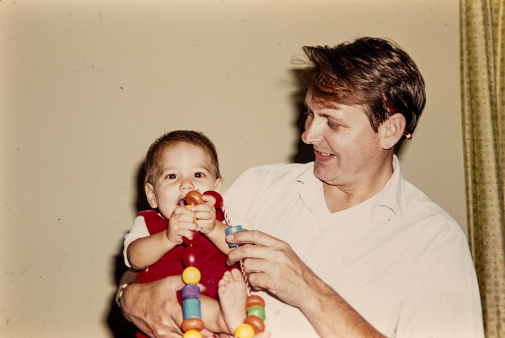 a man holding a baby with a toy in his hands