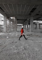 a man in a red jacket is walking through a construction site