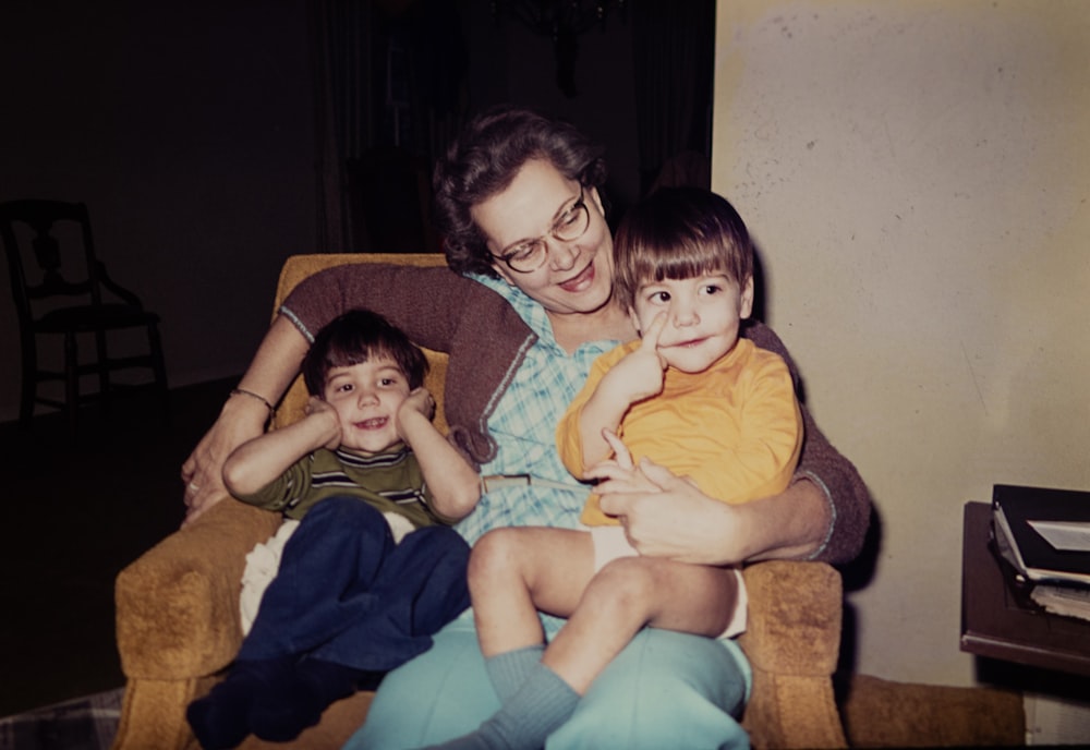 a woman sitting in a chair with two children