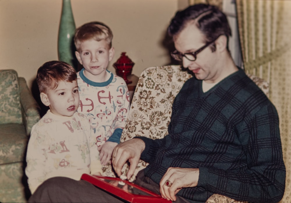 a man sitting on a couch with two boys