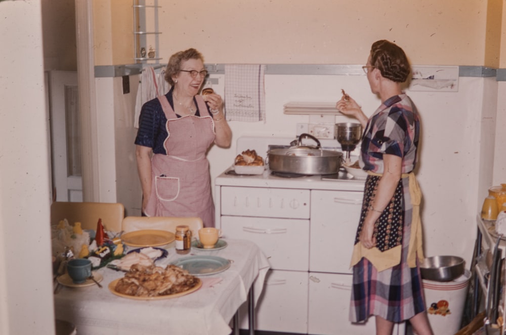 a couple of women standing in a kitchen