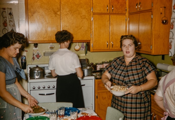 Group of women cooking together in a rustic kitchen.