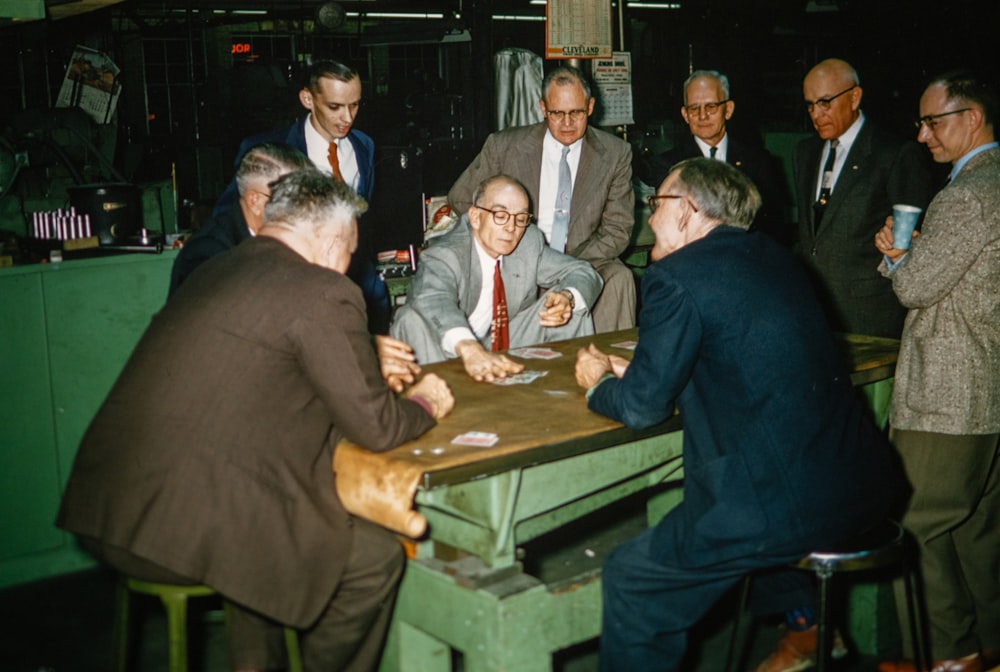 a group of men sitting around a table playing cards