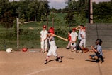 Youth team members practicing batting drills on a sunny field.