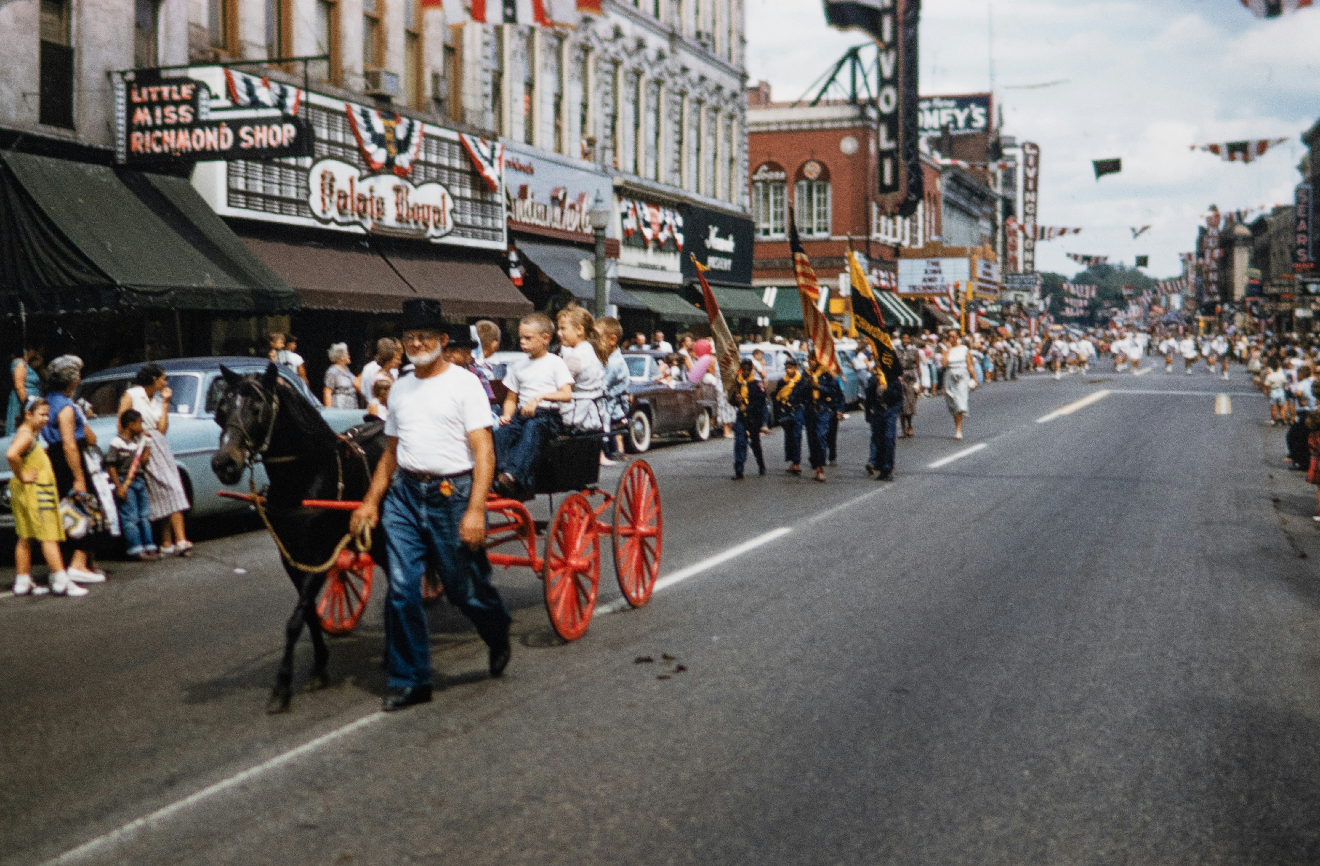 A parade with a horse drawn carriage in the middle of the street photo ...