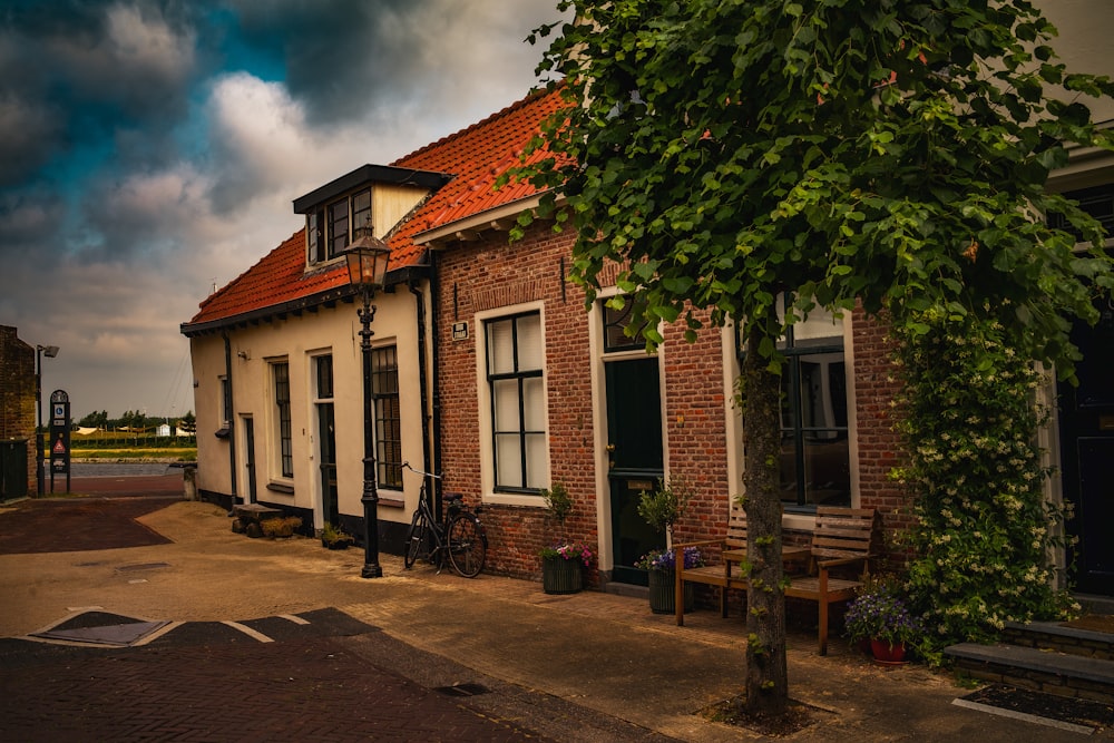 a brick building with a red roof and a tree in front of it