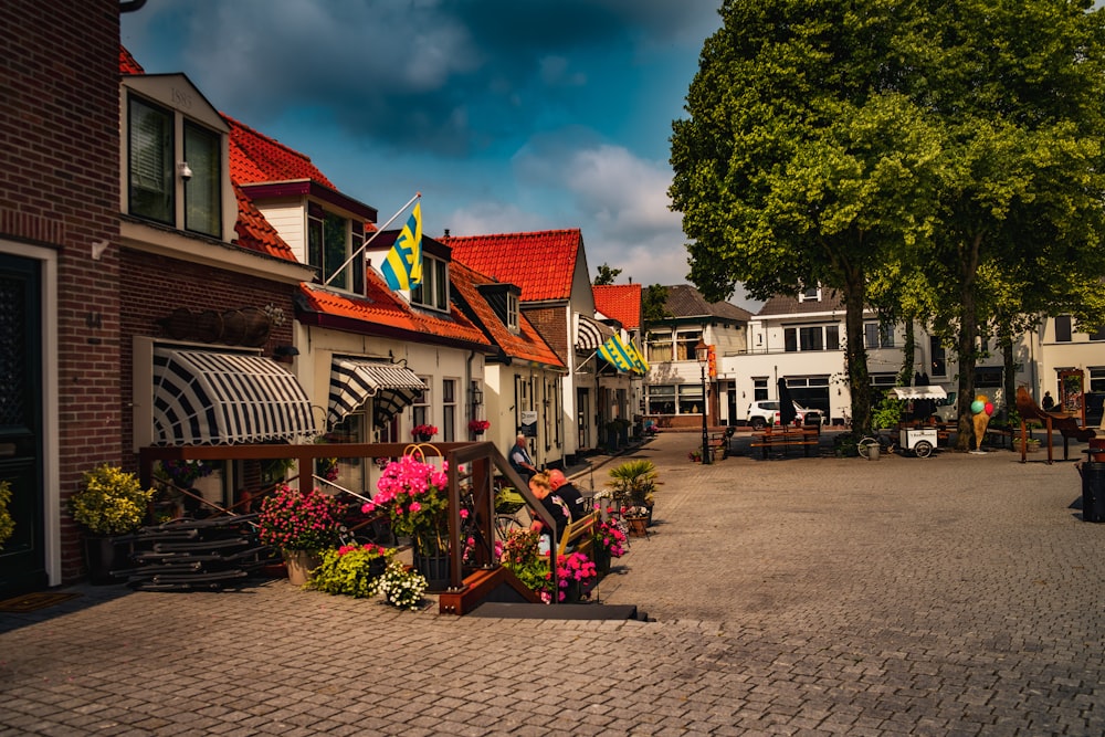a cobblestone street lined with houses and flowers