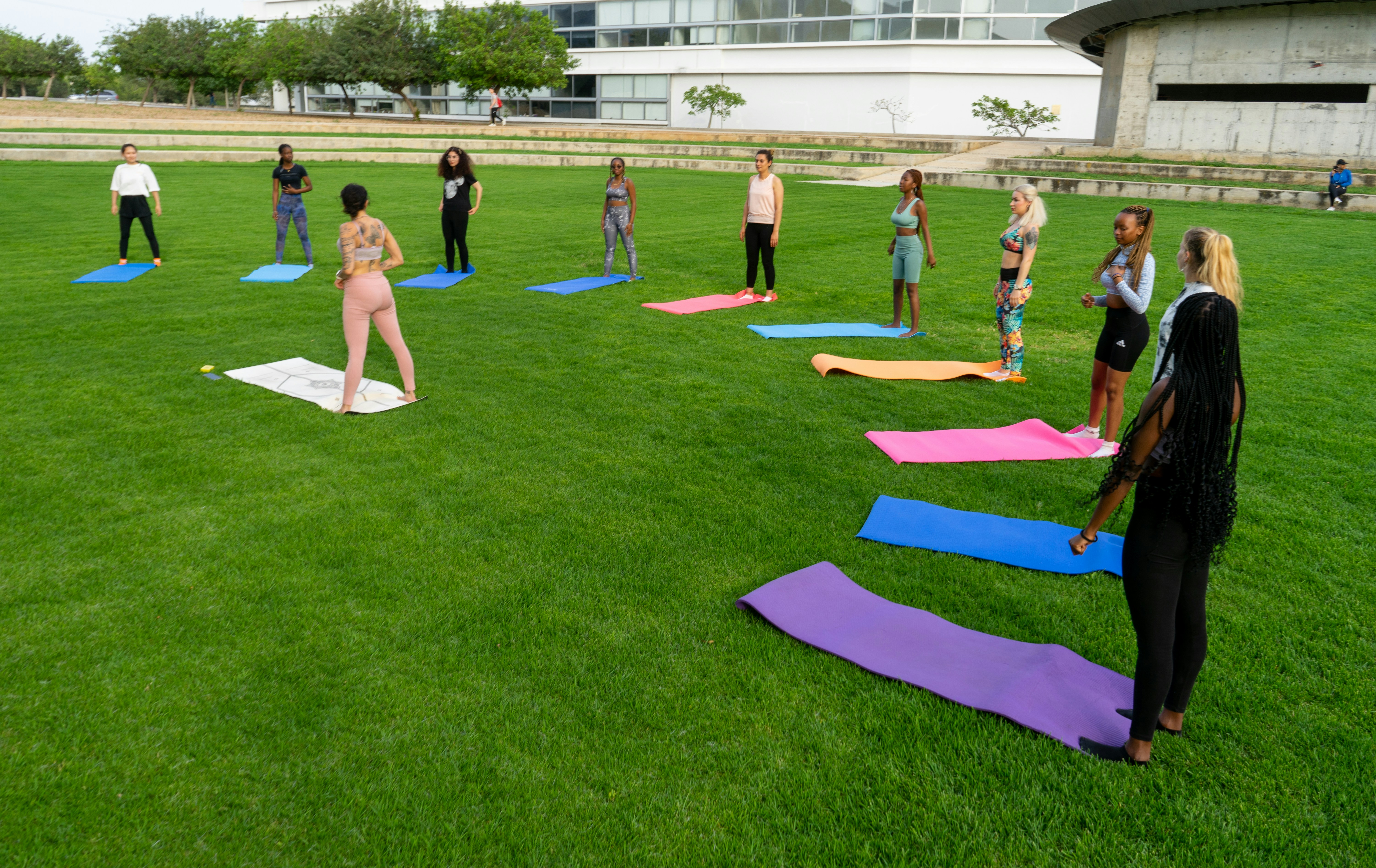 Group yoga class in park with diverse LGBTQ+ participants on colorful yoga mats