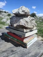 A child balancing books and sports equipment outdoors.