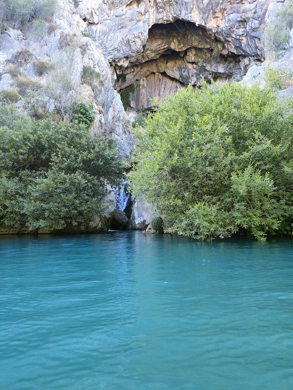 a body of water with a cave in the background