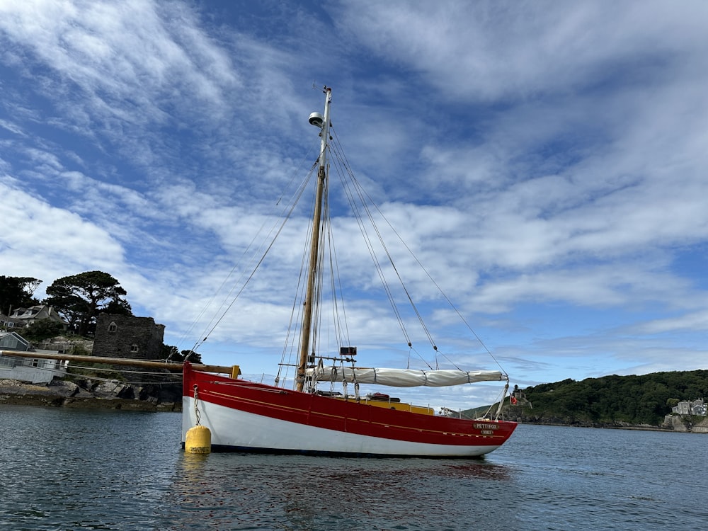 a red and white boat floating on top of a body of water