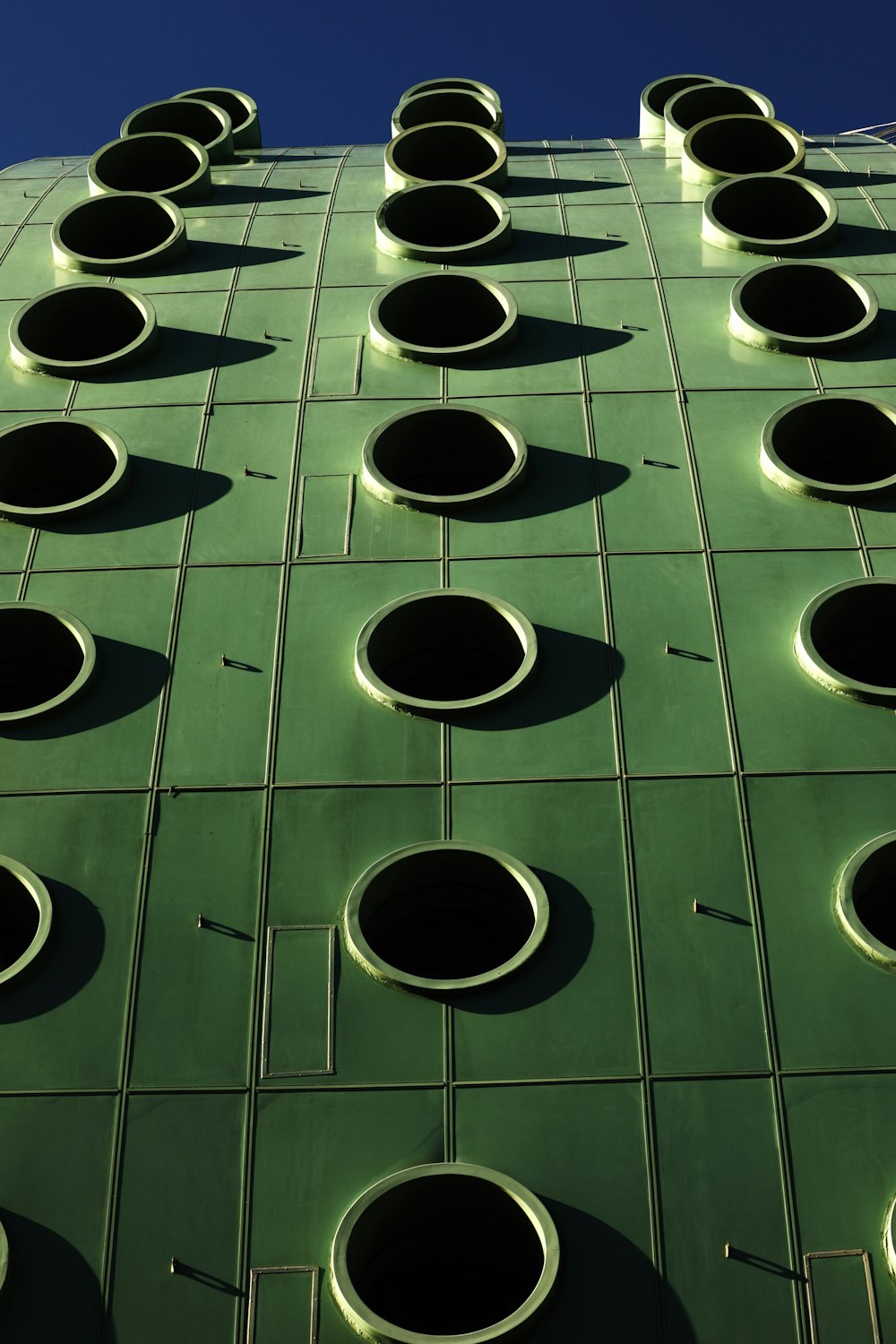 a green building with round windows and a blue sky in the background