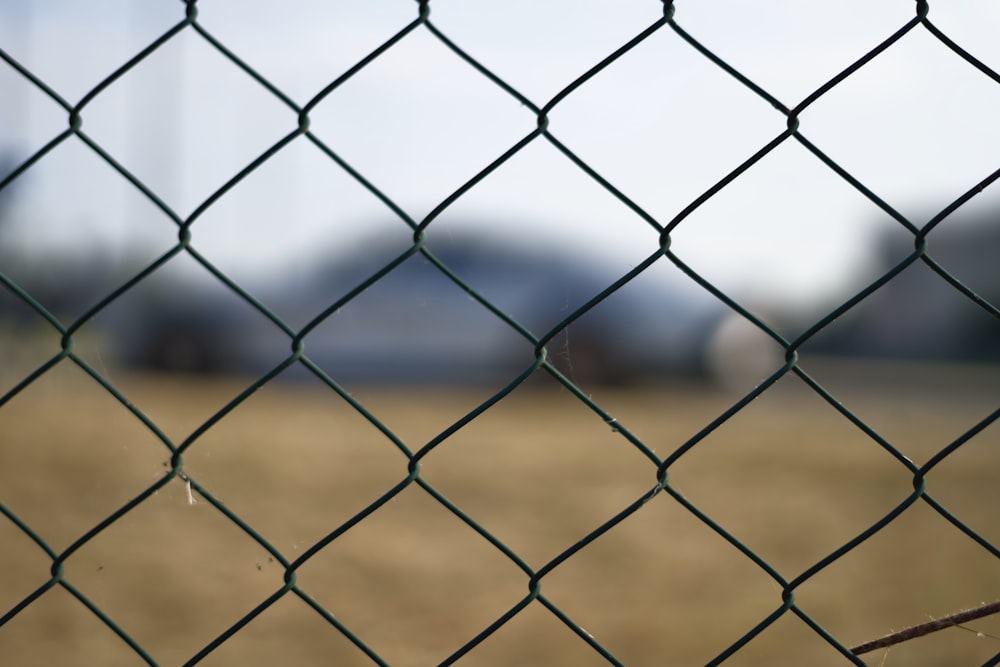 a close up of a fence with a building in the background