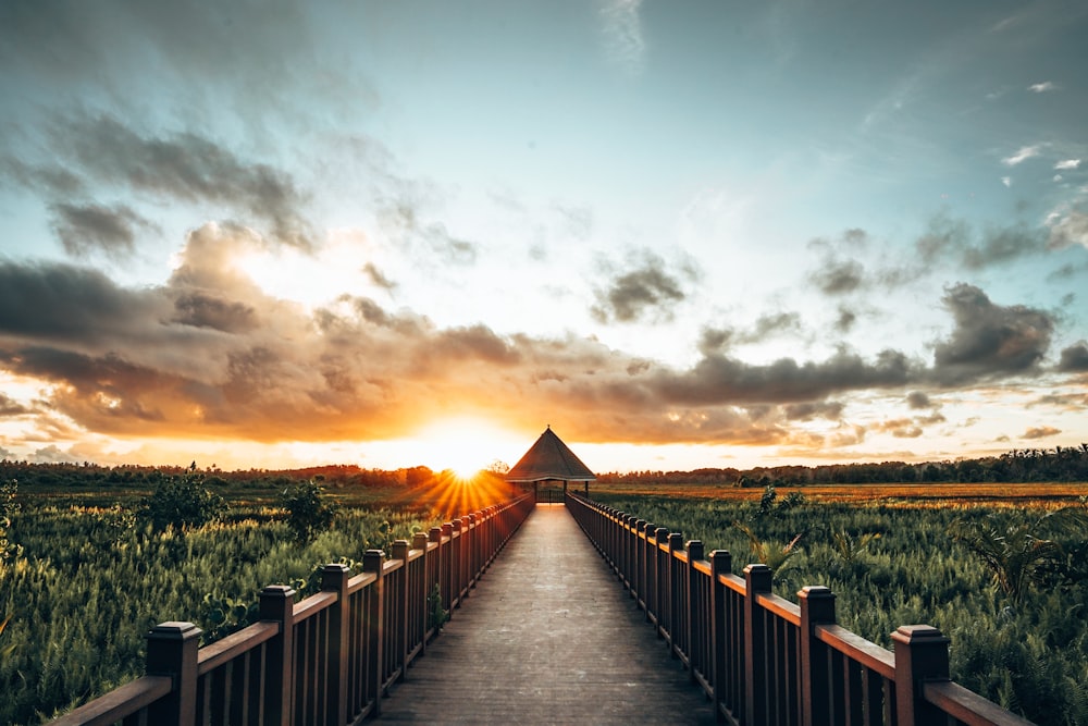 a wooden bridge with a sunset in the background