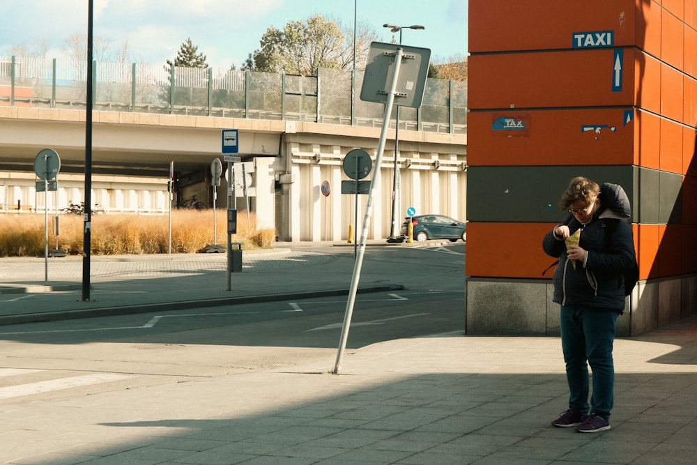 a woman standing on a sidewalk holding a cell phone