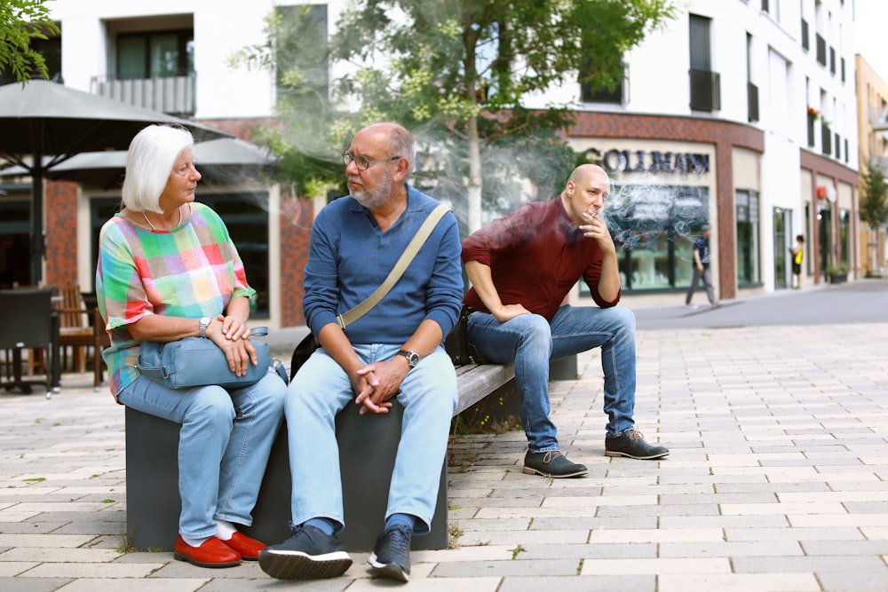 three people sitting on a bench talking to each other