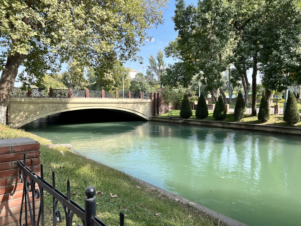 a bridge over a river next to a lush green park