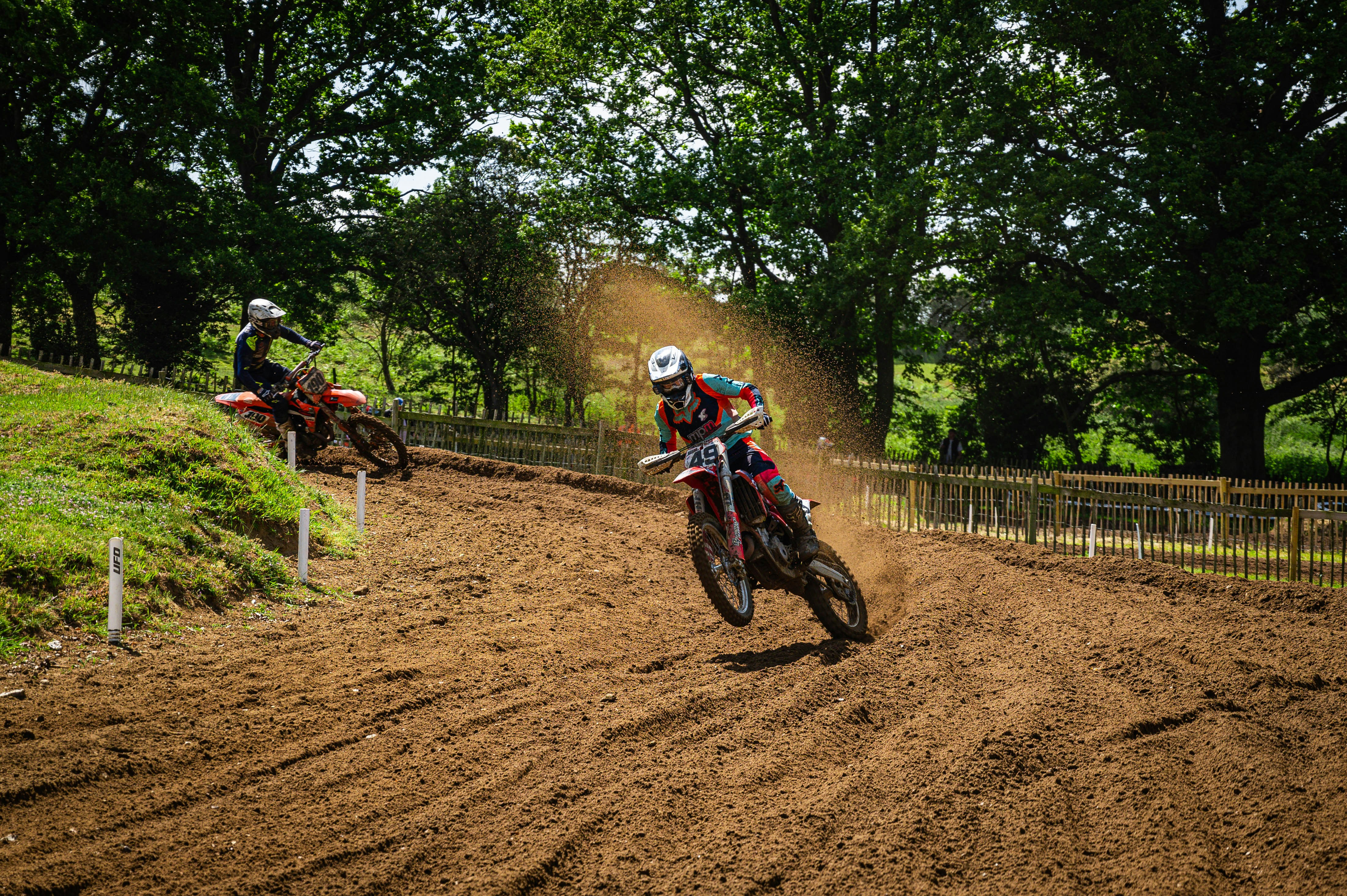 two people riding dirt bikes on a dirt track