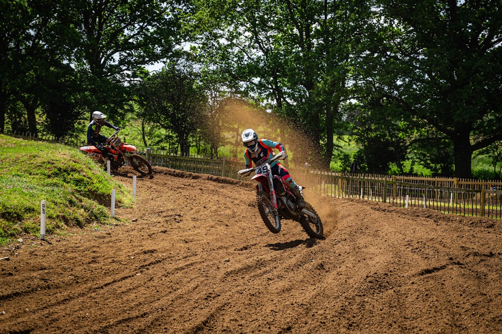 two people riding dirt bikes on a dirt track