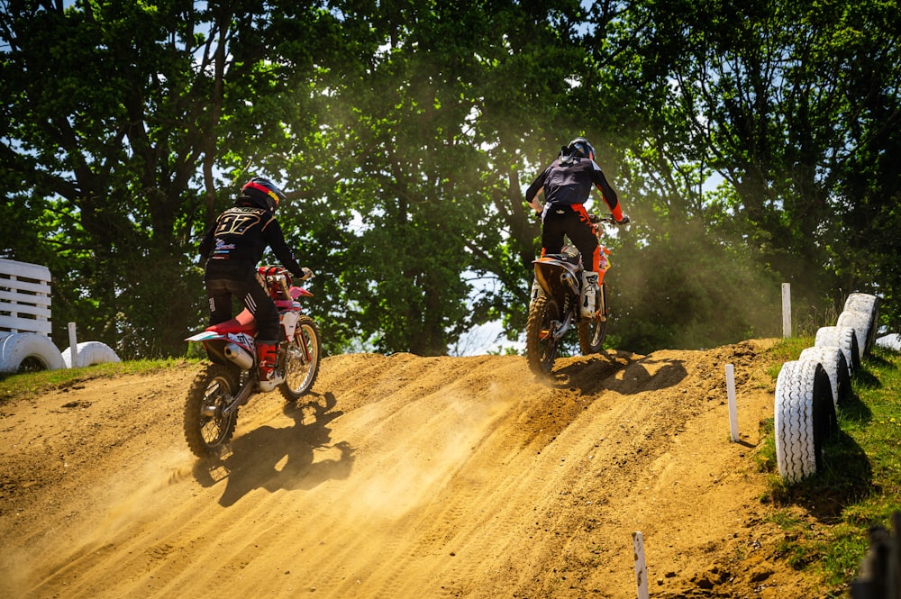 two people riding dirt bikes on a dirt track