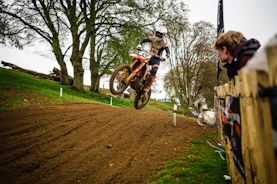 A dynamic motocross rider jumping over a dirt track in a lush green forest