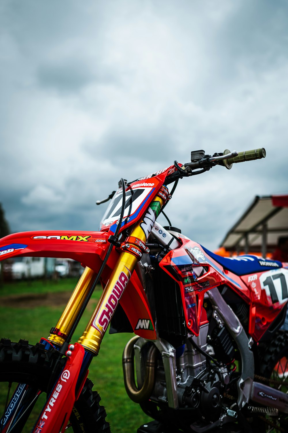 a red dirt bike parked on top of a lush green field