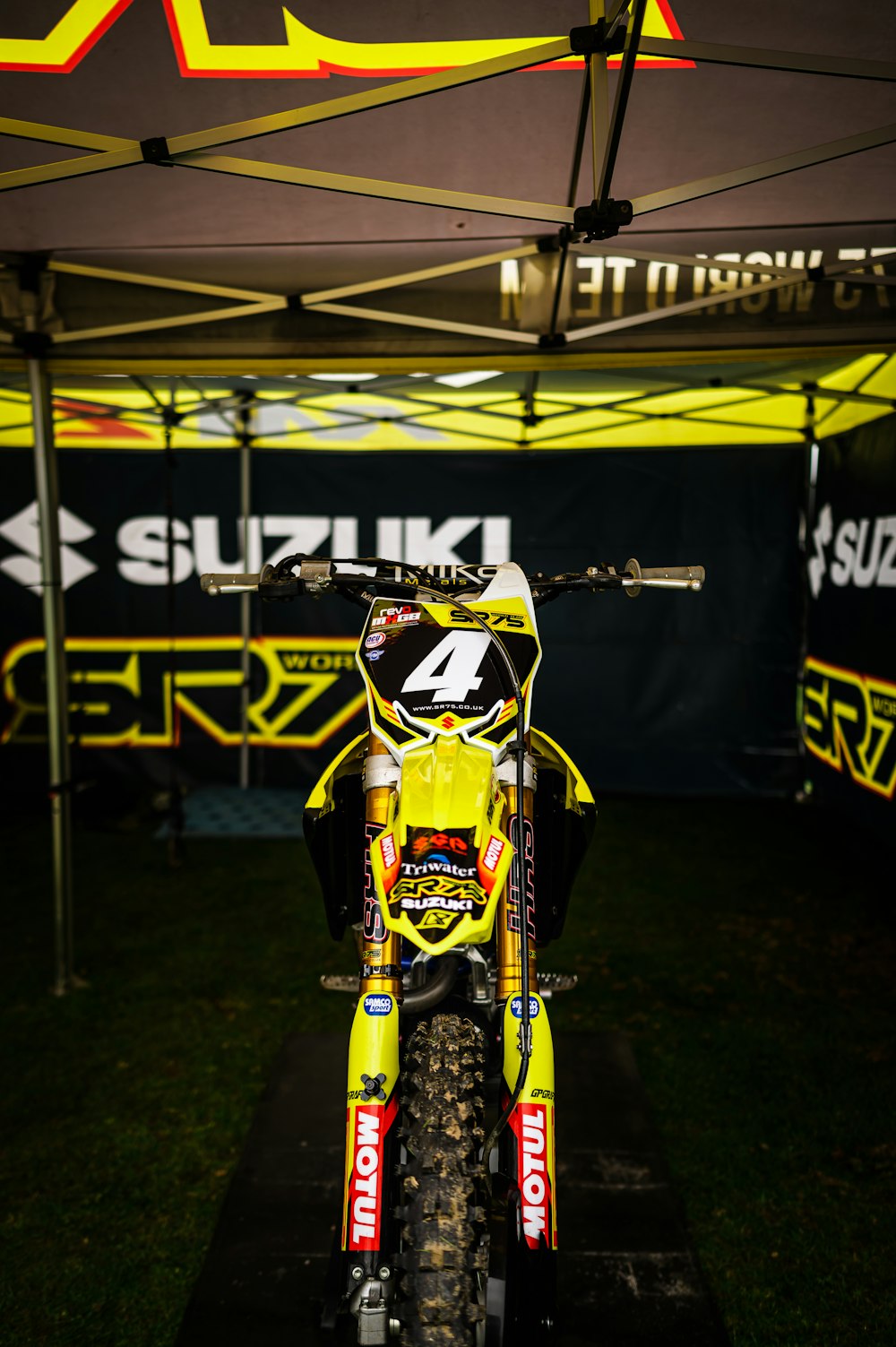 a yellow dirt bike parked under a tent