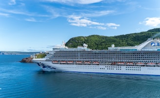 A luxury cruise ship cutting through crystal-clear aqua waters near tropical shores.