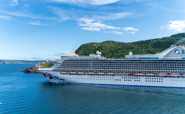 A panoramic view of a sleek cruise ship sailing through crystal-clear blue waters.