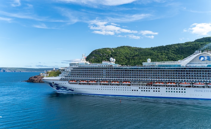 A vibrant cruise ship sailing past tropical islands under a clear blue sky